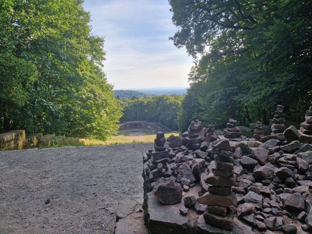 Steinstapel am Ende einer Steigeung mit einem Blick im Hintergrund auf die Landschaft, Blick von oben

